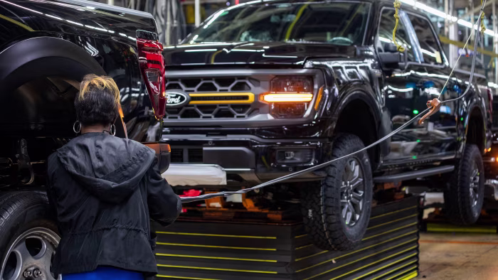Ford to take $19.5bn hit as US carmaker overhauls EV strategy A worker assembles a new black Ford F-150 truck on the production line at the Ford Dearborn Plant.