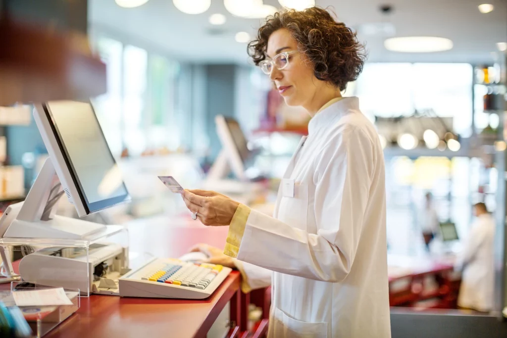 Mature chemist working at the pharmacy checkout counter
