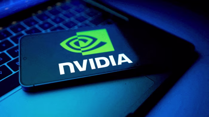 US lawmakers question basis for allowing sale of Nvidia H200 chips to China NVIDIA logo displayed on a smartphone screen, with the device resting on a laptop keyboard in a blue-lit setting.
