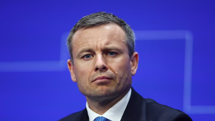 Ukraine seals restructuring of controversial growth-linked debt Serhiy Marchenko appears serious while attending the Ukraine Recovery Conference against a blue background.