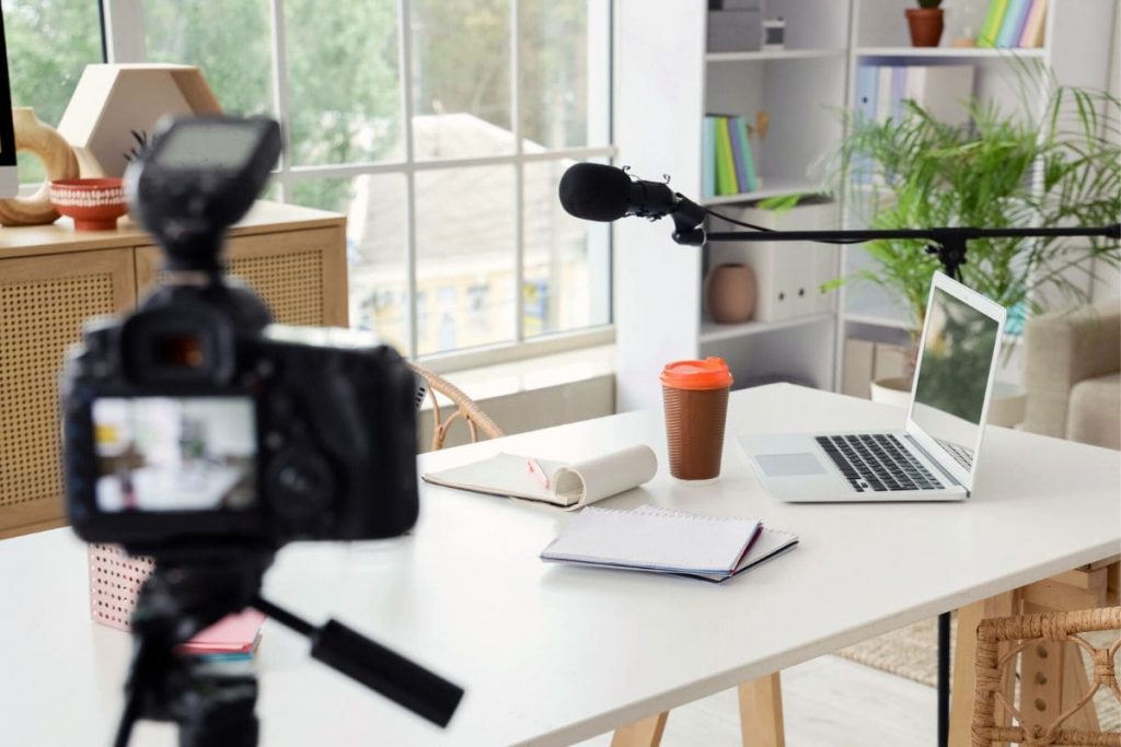 A content creator's home office desk, with a camera, microphone, and laptop.