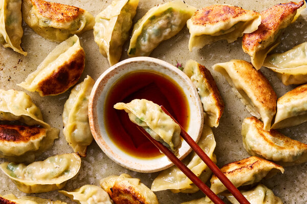 5 New Dumpling Recipes for Lunar New Year 2026 Several beautiful platters topped with different types of dumplings sit on a rich green surface.