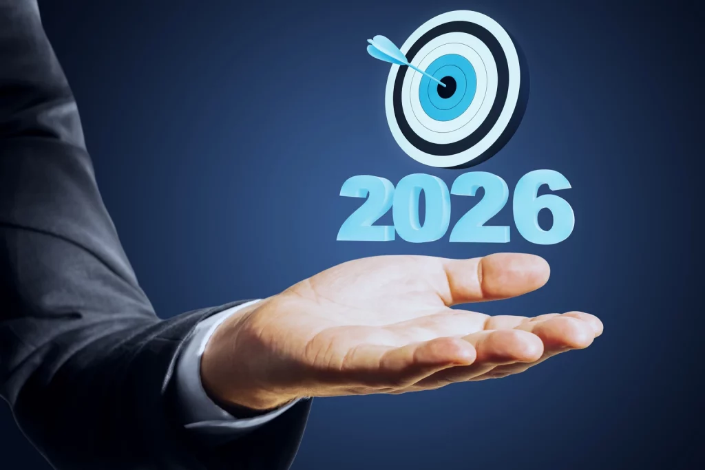 Businessman holding out hand with 2026 target and dart symbolizing future goals and achievement on dark background in conceptual image.