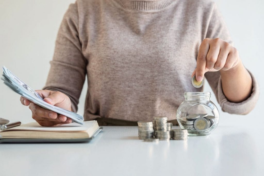 Closeup of a woman counting money at a home office desk.