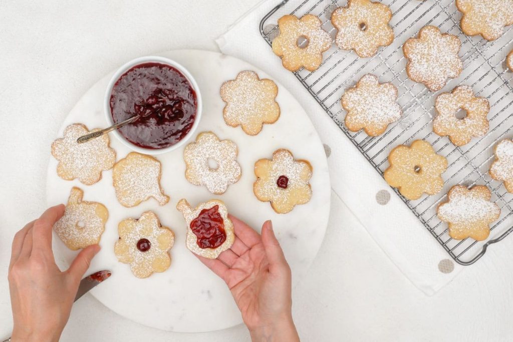 Overhead view of a woman's hands, decorating shortbread cookies.