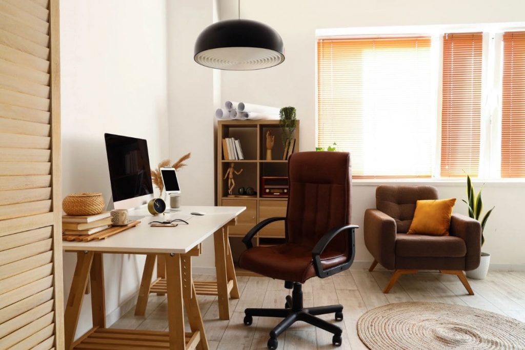 Work From Home Equipment Checklist for Remote Workers A home office setup, with a desktop computer, webcam, ergonomic chair, and a bookshelf.